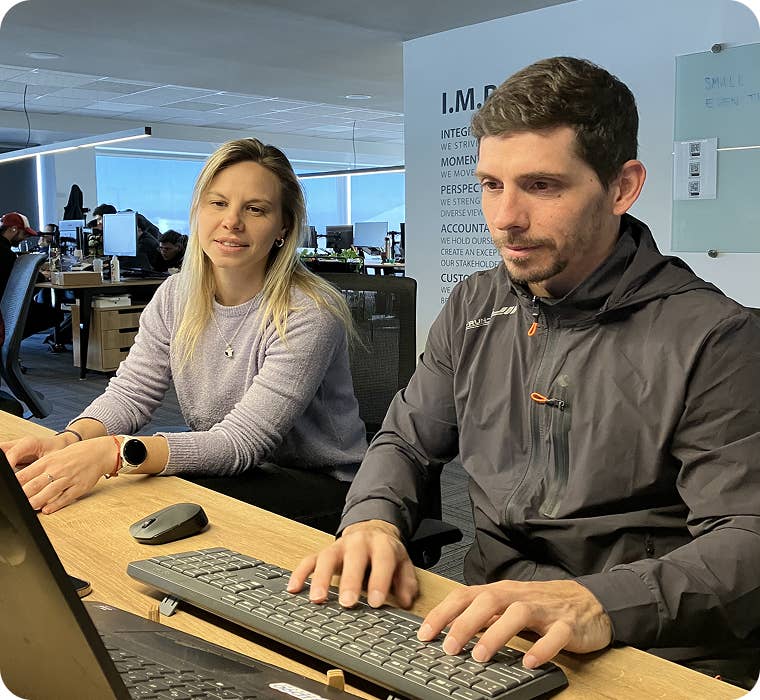 Two ID90 Travel employees working together in an open office environment.