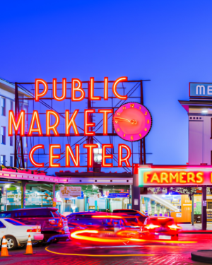 Public Market Center sign at Pike Place Market with neon clock and bustling market entrance