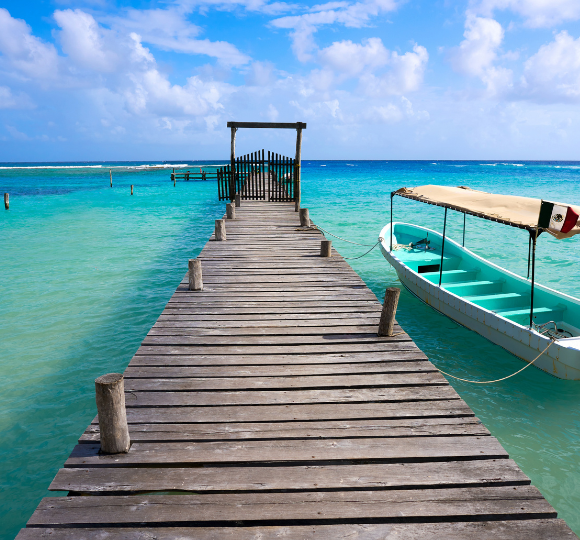 Wooden pier extending into bright blue Caribbean waters under a clear sky
