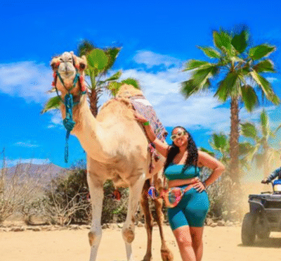 Traveler riding a camel across sandy desert terrain near the coast