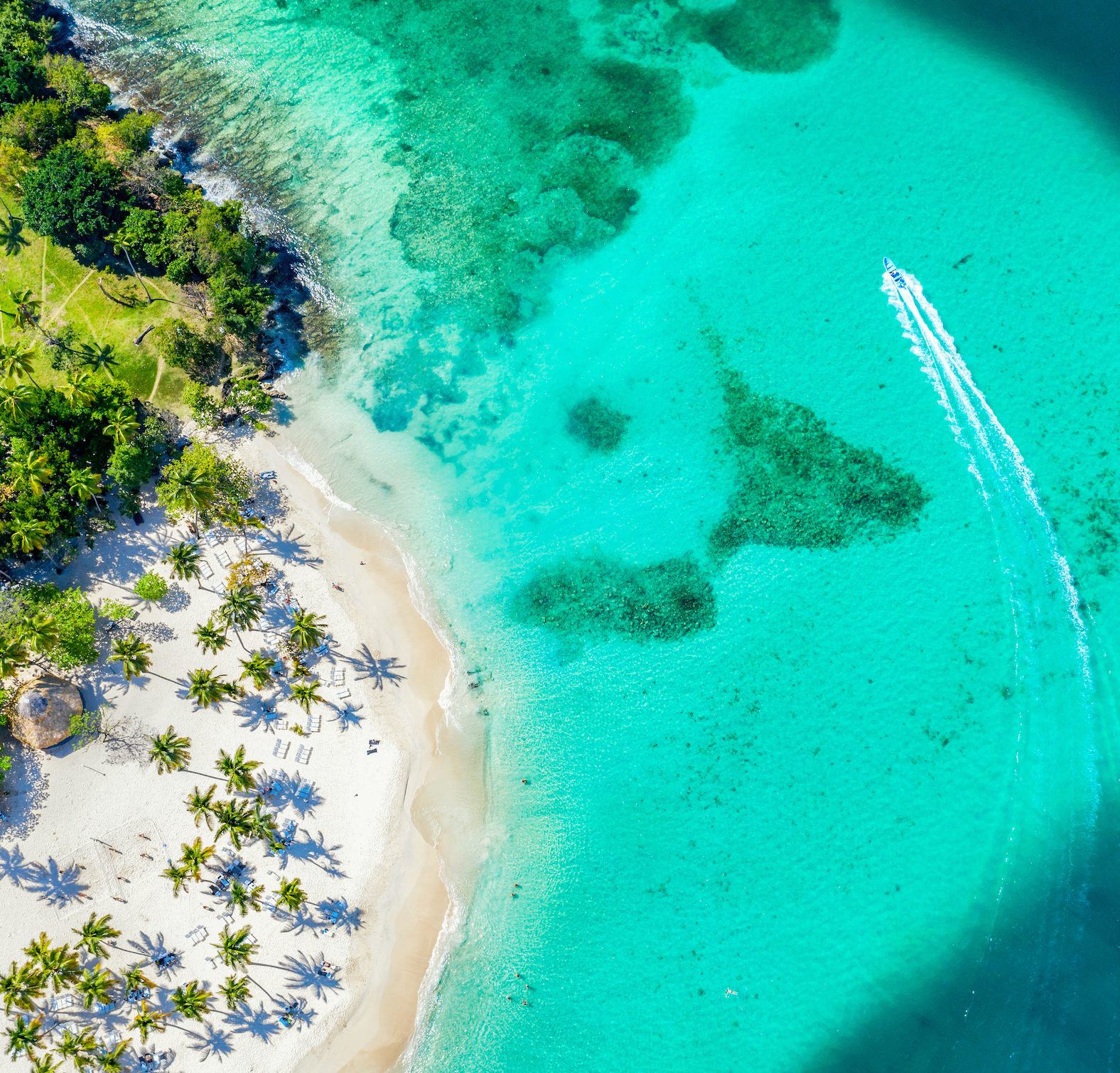 Crystal-clear blue water meeting soft white sand under a bright tropical sky