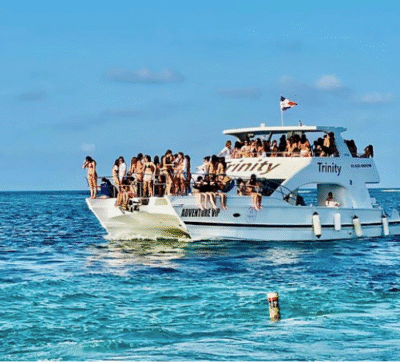Group of adults enjoying music and drinks on a boat in turquoise water