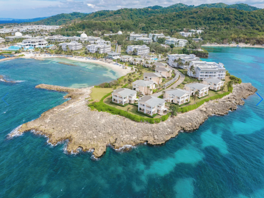 Aerial view of Jamaica’s turquoise coastline and lush green mountains meeting the Caribbean Sea