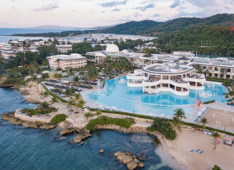 Expansive beachfront view of Grand Palladium Resort in Jamaica with palm trees and ocean backdrop