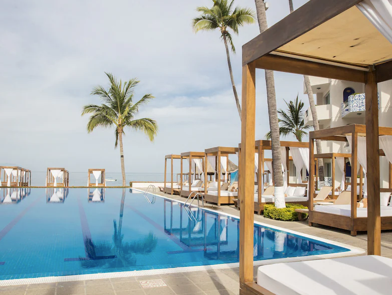 Adults-only resort pool with lounge chairs, palm trees, and tropical ambiance