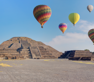 Hot air balloons floating above the Teotihuacan pyramids near Mexico City at sunrise.
