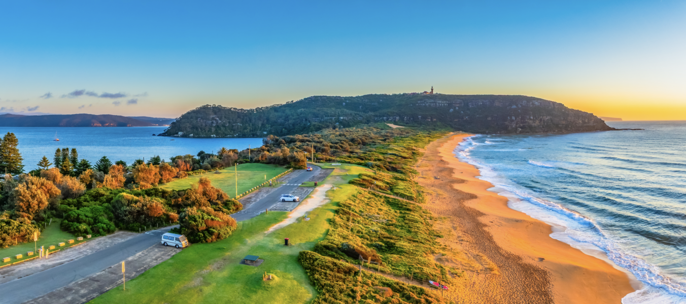 Sandy beach in Sydney with turquoise water, rolling waves, and people enjoying the shoreline