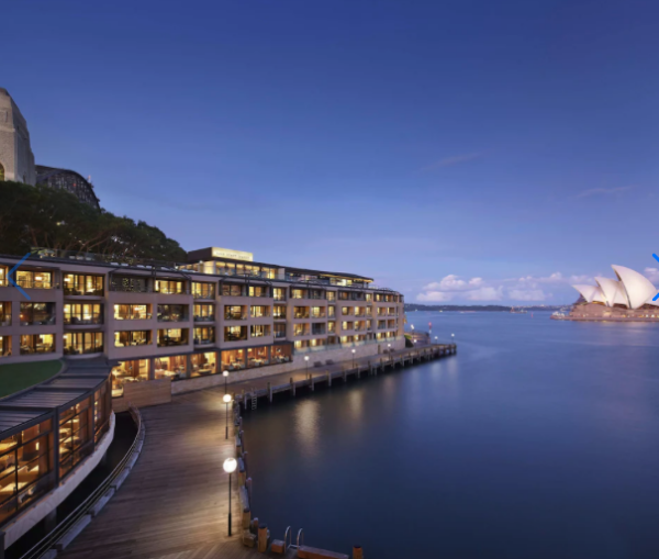 Sydney waterfront promenade with boats in the harbor and city skyline in the background