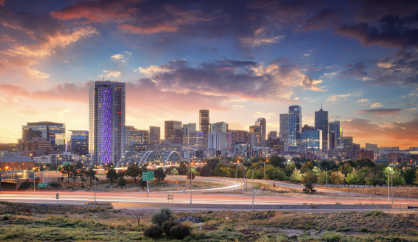 Denver skyline at sunset with city lights and mountains in the background