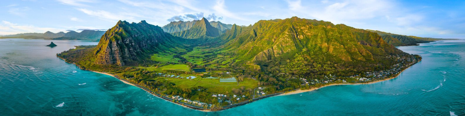 Panoramic view of Oahu, Hawaii, featuring turquoise ocean water, sandy beaches, and lush green mountains under a clear blue sky.