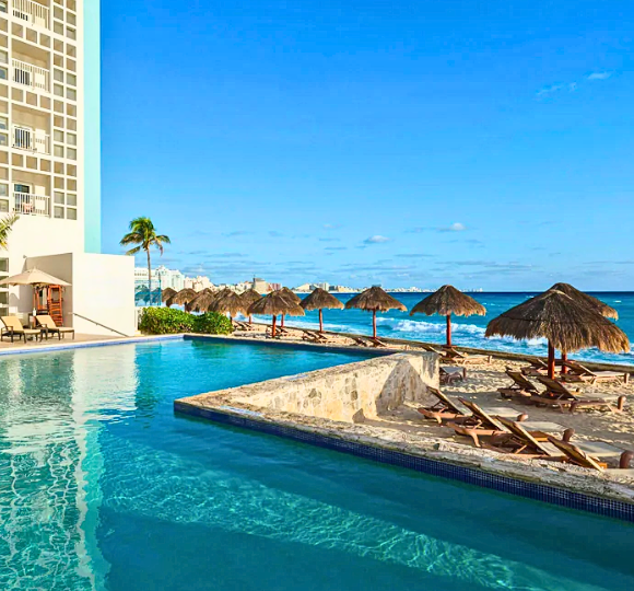 The Westing Resort & Spa pool overlooking the beach with tiki stands surrounding the beach chairs.