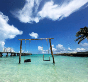 Wooden swings set in shallow turquoise waters along a sunny Cancun beach