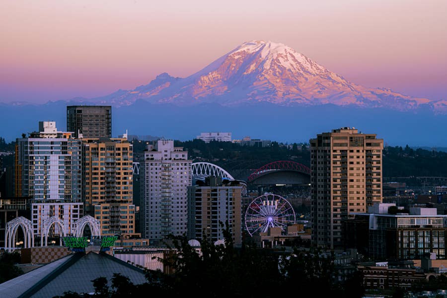 Snow-capped mountain rising above a forested landscape under a clear sky