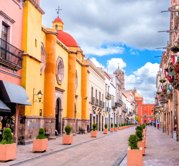 Bustling Mexico City street lined with colorful buildings, shops, and everyday city life.
