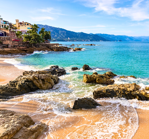 Golden sand beach in Puerto Vallarta with turquoise water and gentle waves under a bright blue sky