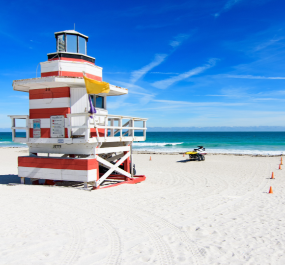 Soft white sand beach meeting clear blue ocean waters under sunny skies