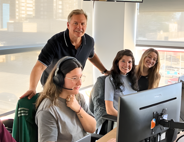Mike Stacey standing with customer support team members working at computers in an office environment