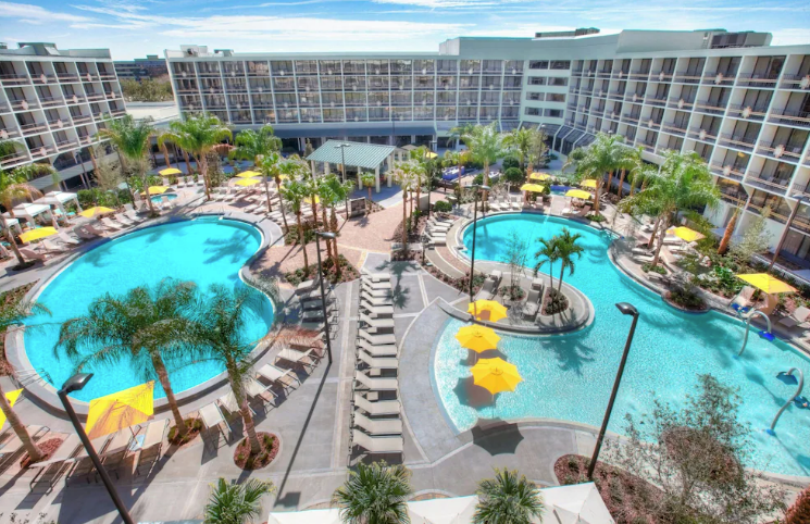 Sheraton Orlando hotel with two resort-style pools, founders and palm trees surrounding.